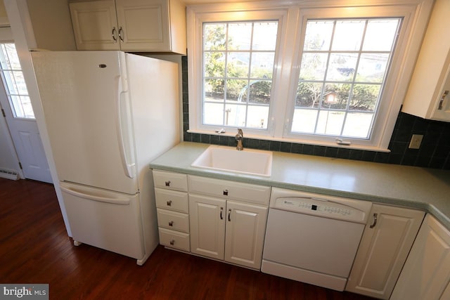 kitchen with a sink, white appliances, and white cabinets