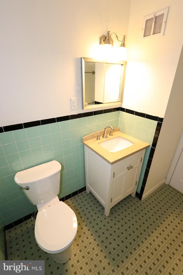 bathroom with visible vents, toilet, wainscoting, and vanity