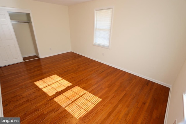 unfurnished bedroom with a closet, baseboards, and wood finished floors