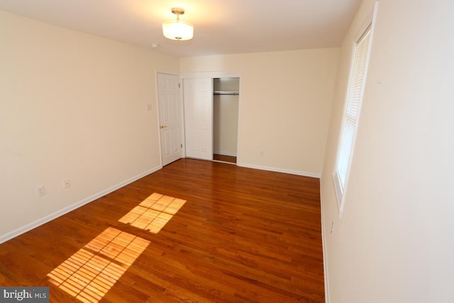 unfurnished bedroom with a closet, baseboards, and wood finished floors