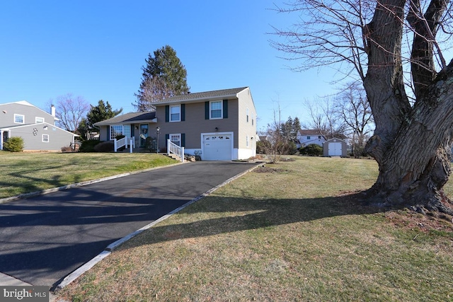 tri-level home featuring an outbuilding, an attached garage, a front yard, and driveway