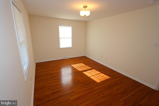 spare room featuring visible vents, wood finished floors, and baseboards