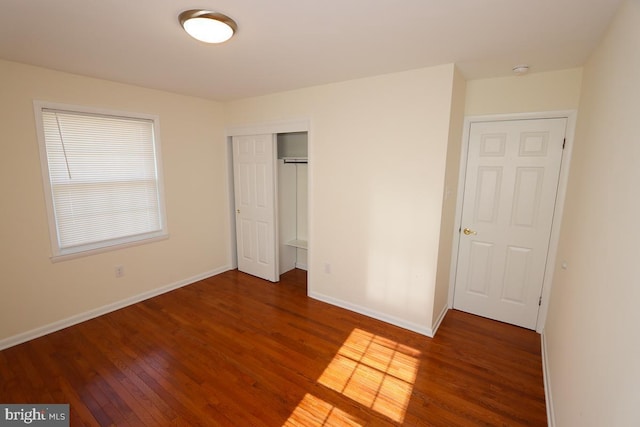 unfurnished bedroom with a closet, baseboards, and wood finished floors