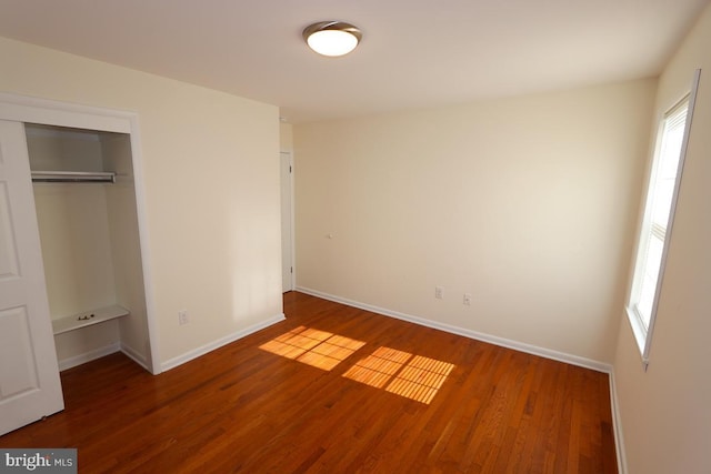 unfurnished bedroom featuring wood finished floors, a closet, and baseboards