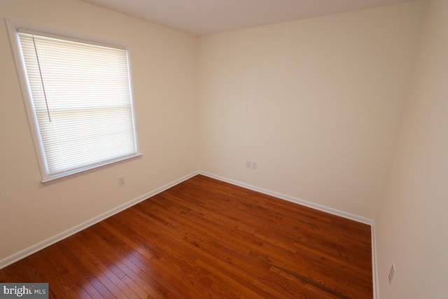 spare room with hardwood / wood-style flooring and baseboards