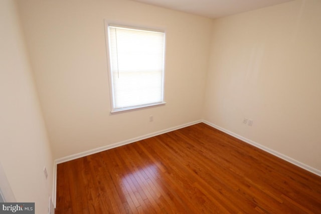 spare room with hardwood / wood-style flooring and baseboards