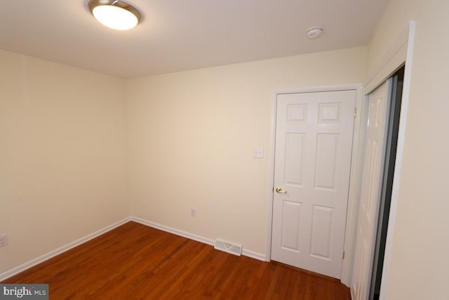 empty room featuring visible vents, baseboards, and dark wood-type flooring