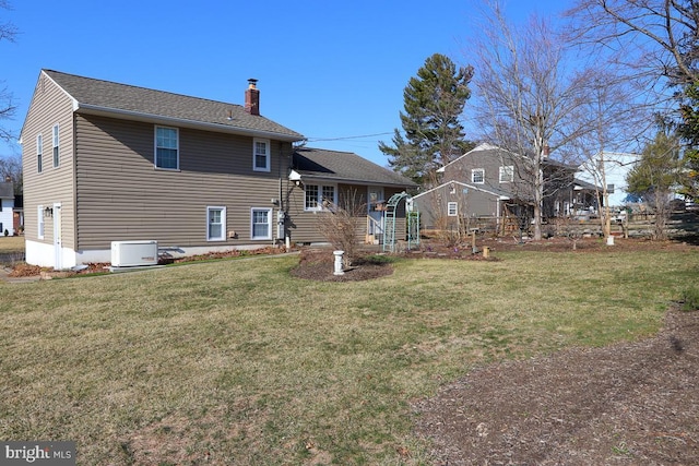 rear view of house featuring a lawn and a chimney