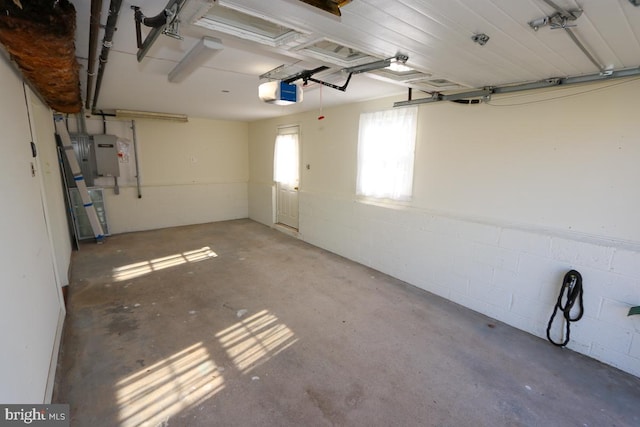 garage featuring electric panel, a garage door opener, and concrete block wall