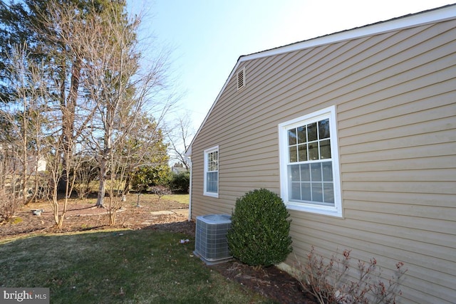 view of property exterior with central AC unit and a lawn