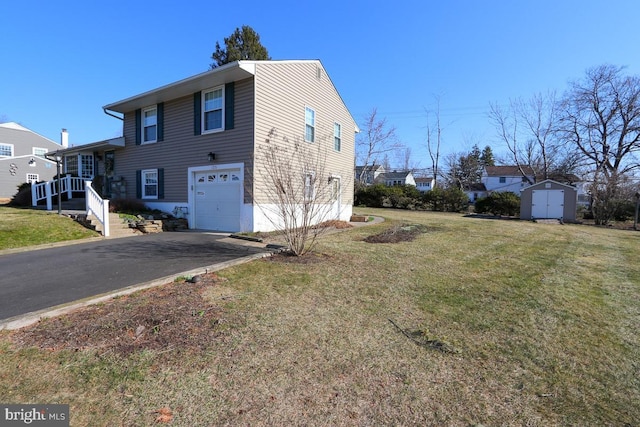 view of front of home with a storage unit, an outbuilding, driveway, a front yard, and a garage