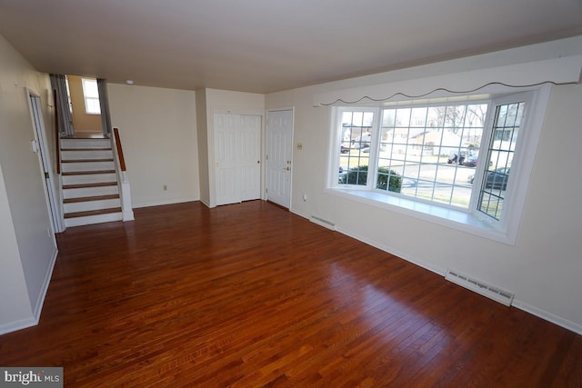 unfurnished living room featuring stairs, dark wood-style floors, visible vents, and baseboards