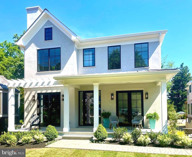 modern inspired farmhouse featuring covered porch, a chimney, a pergola, and stucco siding