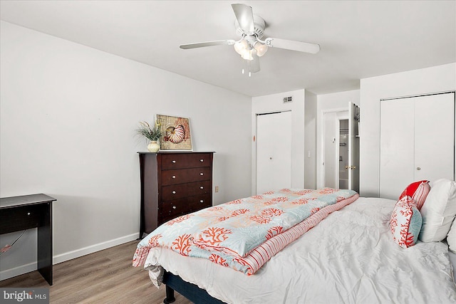 bedroom with ceiling fan, wood finished floors, baseboards, and multiple closets