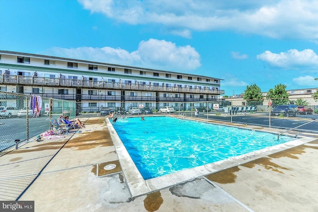 view of swimming pool featuring a patio and fence