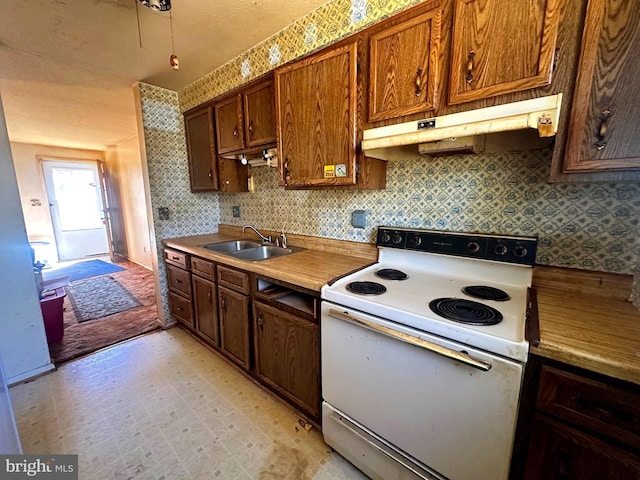 kitchen with light floors, electric range, decorative backsplash, a sink, and under cabinet range hood