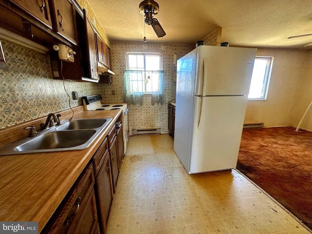 kitchen featuring light floors, white appliances, a sink, and wallpapered walls