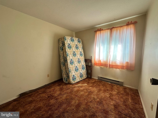 spare room featuring a baseboard heating unit, carpet flooring, a textured ceiling, and baseboards