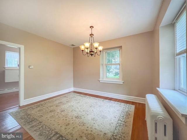 6 Washington Ave, Norristown, PA 19403 - unfurnished dining area featuring radiator heating unit, healthy amount of natural light, a chandelier, and wood finished floors