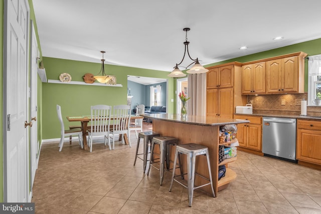 kitchen featuring a kitchen bar, tasteful backsplash, dishwasher, and light tile patterned flooring