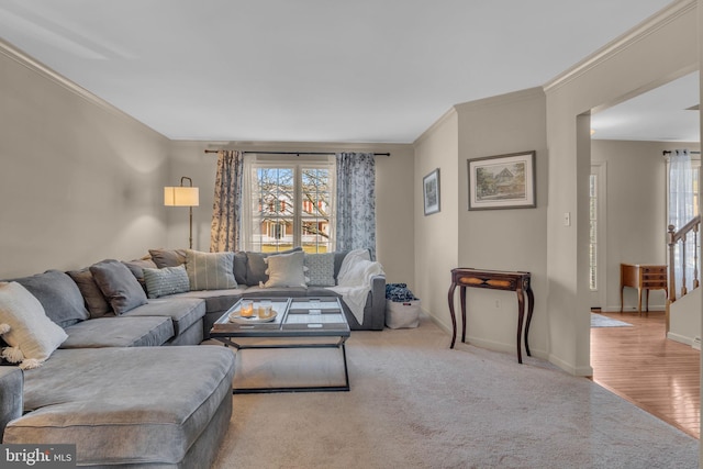 carpeted living room with stairs, baseboards, and ornamental molding