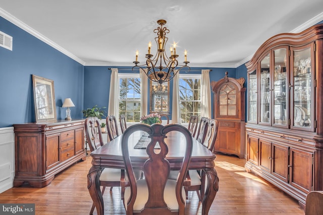 dining room featuring light wood-style floors, a notable chandelier, and crown molding