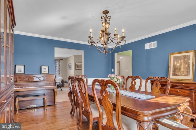 dining room with visible vents, a chandelier, a wainscoted wall, ornamental molding, and wood finished floors