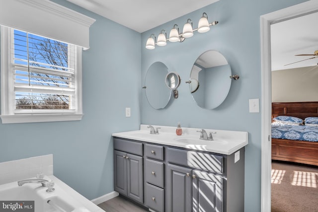 bathroom with double vanity, connected bathroom, ceiling fan, and a sink