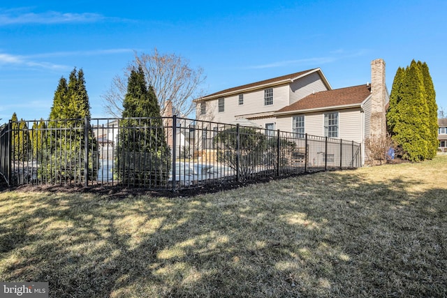 back of property with a lawn and fence