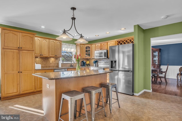 kitchen with a center island, glass insert cabinets, a breakfast bar area, dark stone countertops, and appliances with stainless steel finishes