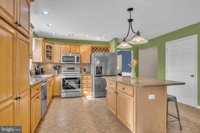 kitchen with a kitchen island, a breakfast bar, a sink, glass insert cabinets, and appliances with stainless steel finishes