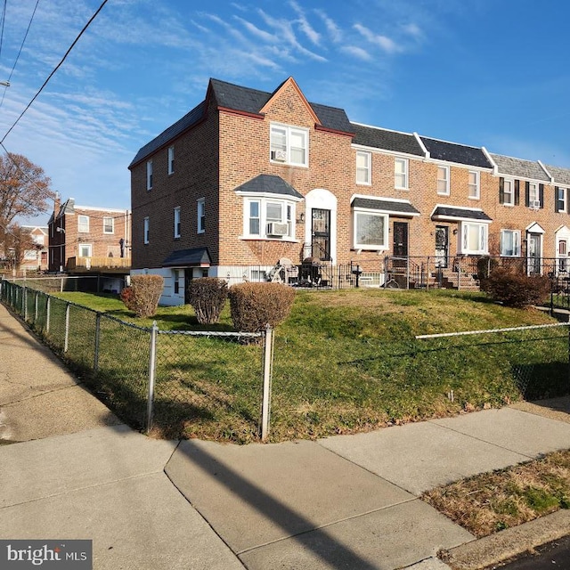 townhome / multi-family property with a fenced front yard, a residential view, brick siding, and a front lawn