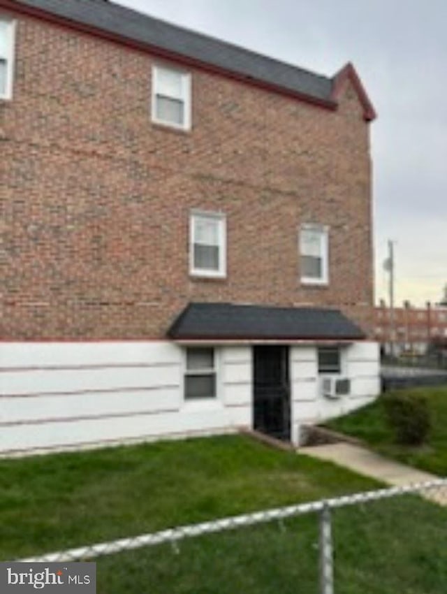 rear view of property with a lawn and brick siding