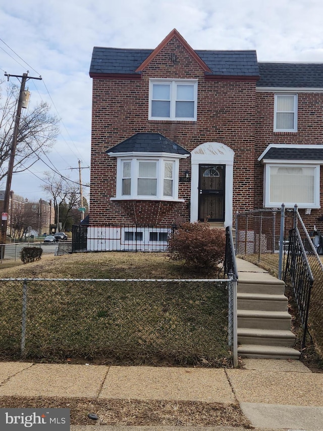 view of front of home featuring a fenced front yard, brick siding, a shingled roof, and mansard roof