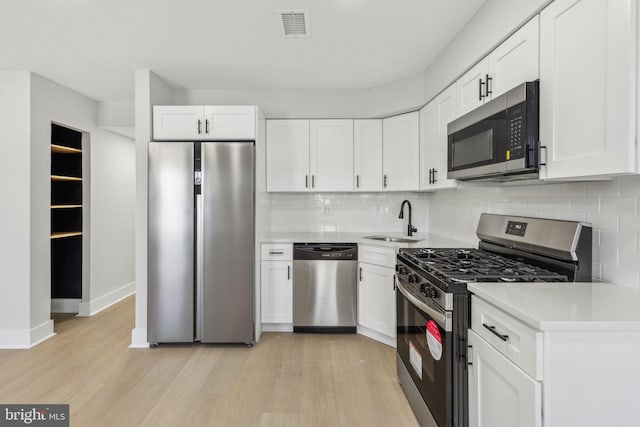 kitchen with a sink, light wood-style floors, visible vents, and stainless steel appliances