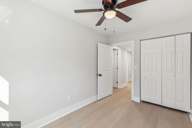 unfurnished bedroom with light wood-style flooring, baseboards, a closet, and ceiling fan