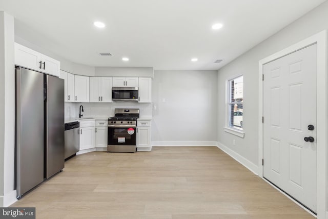 kitchen featuring visible vents, light countertops, stainless steel appliances, white cabinetry, and a sink