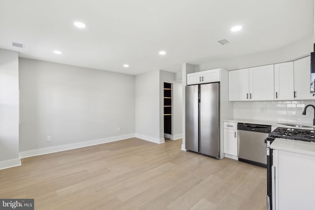 kitchen featuring light wood-type flooring, a sink, stainless steel appliances, light countertops, and tasteful backsplash