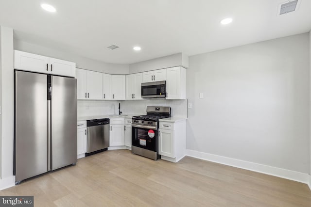 kitchen with visible vents, backsplash, stainless steel appliances, white cabinets, and light countertops