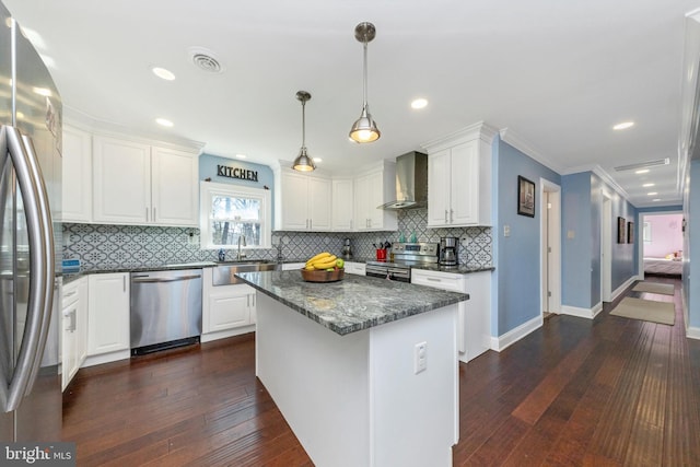 kitchen featuring a sink, appliances with stainless steel finishes, wall chimney exhaust hood, and white cabinetry