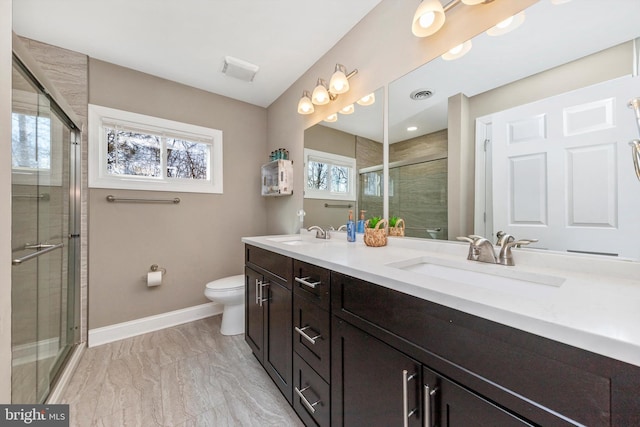 bathroom featuring visible vents, a shower stall, baseboards, toilet, and a sink