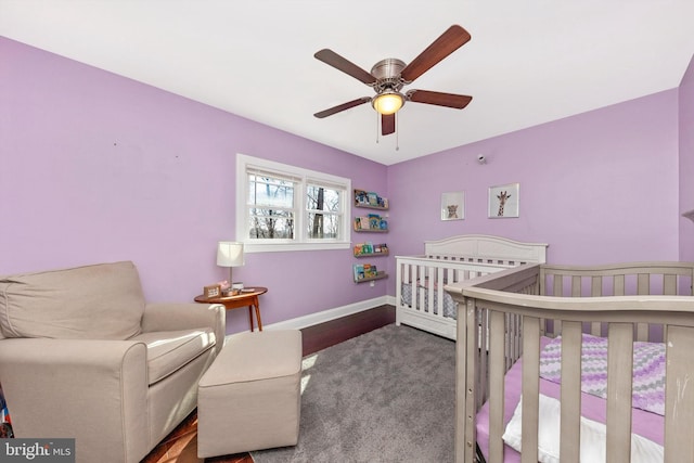 bedroom with a nursery area, a ceiling fan, and baseboards