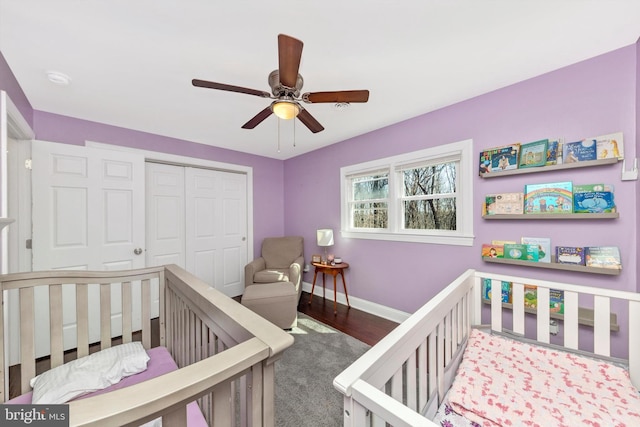 bedroom featuring ceiling fan, baseboards, wood finished floors, a closet, and a nursery area