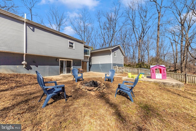 back of house featuring an outdoor fire pit and fence