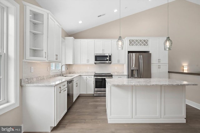 kitchen featuring stainless steel appliances, a kitchen island, a sink, and white cabinetry