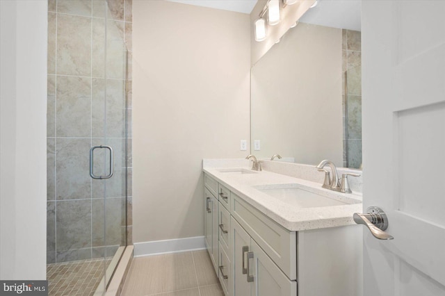 full bathroom with baseboards, double vanity, a sink, and a shower stall