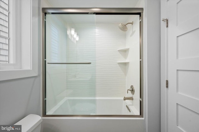 full bath featuring toilet and bath / shower combo with glass door