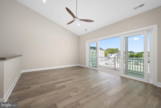 unfurnished room featuring baseboards, visible vents, vaulted ceiling, and wood finished floors