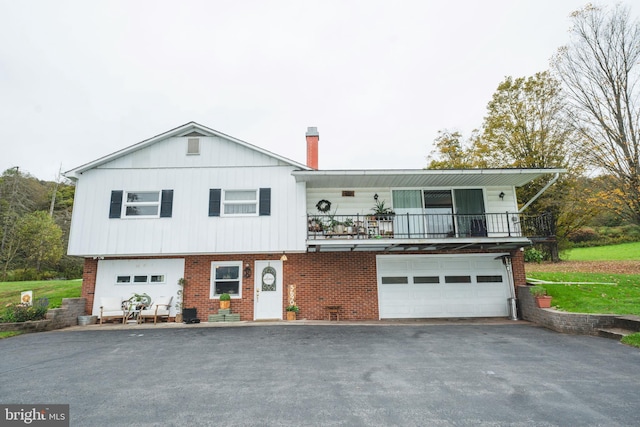 view of front of property with a balcony, brick siding, a garage, and driveway