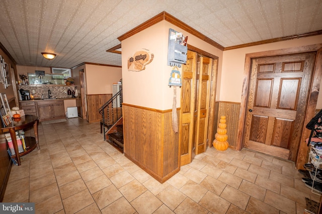 corridor with stairs, wooden walls, a wainscoted wall, and an ornate ceiling